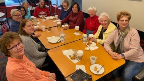 Members sitting at long table at Braeda smile at camera.