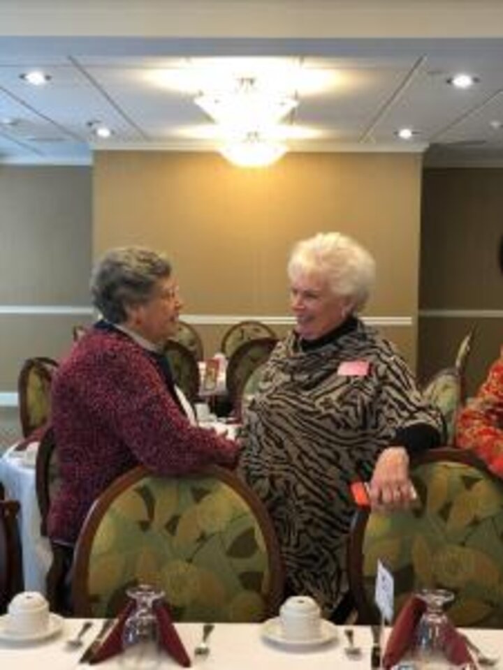 Two women pose in front of brunch table