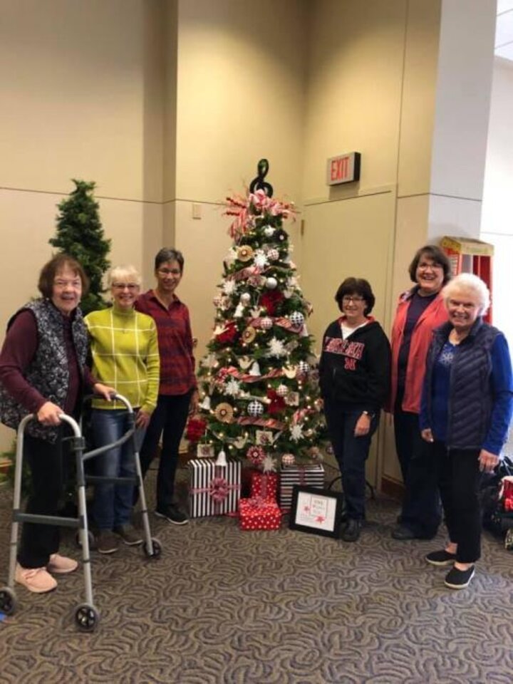 Six club members flank wonderfully decorated Christmas tree.