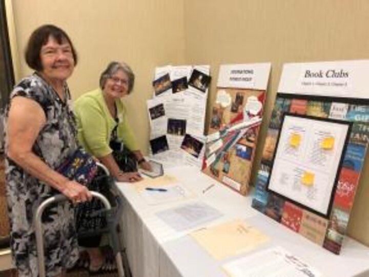Two club members stand in front of table with special activity groups posters