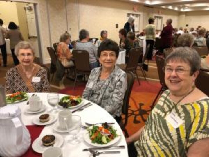 Club members sit at table eating lunch