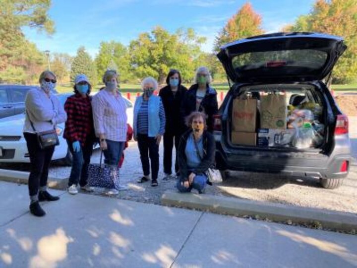 Seven club members pose next to minivan full of donations