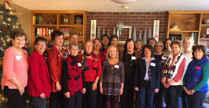 A large group of women pose for photo in home decorated for Christmas.