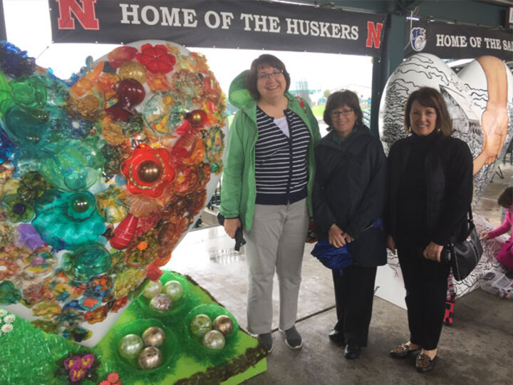 Three women pose next to Lincoln Arts Program heart sculpture.