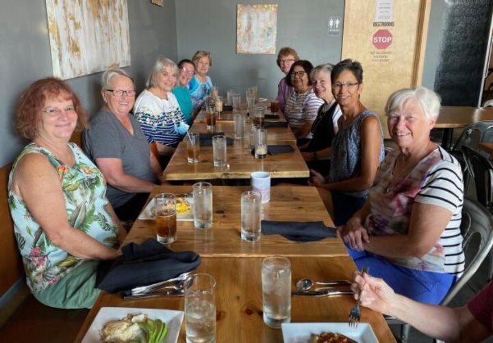 Club members sit at extra long table at Art & Soul