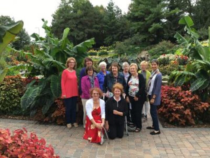Women's Club members pose in front of beautiful flowers at the Sunken Garden.