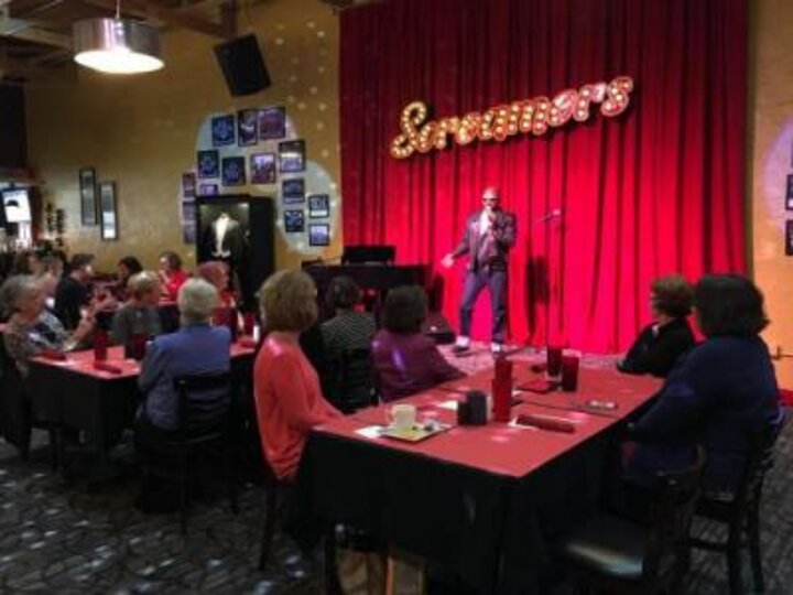 Women's Club watches performer on stage at Screamers Dining and Cabaret.