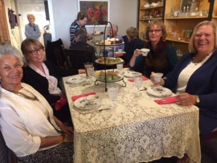 Club members sit at table with well appointed tea service