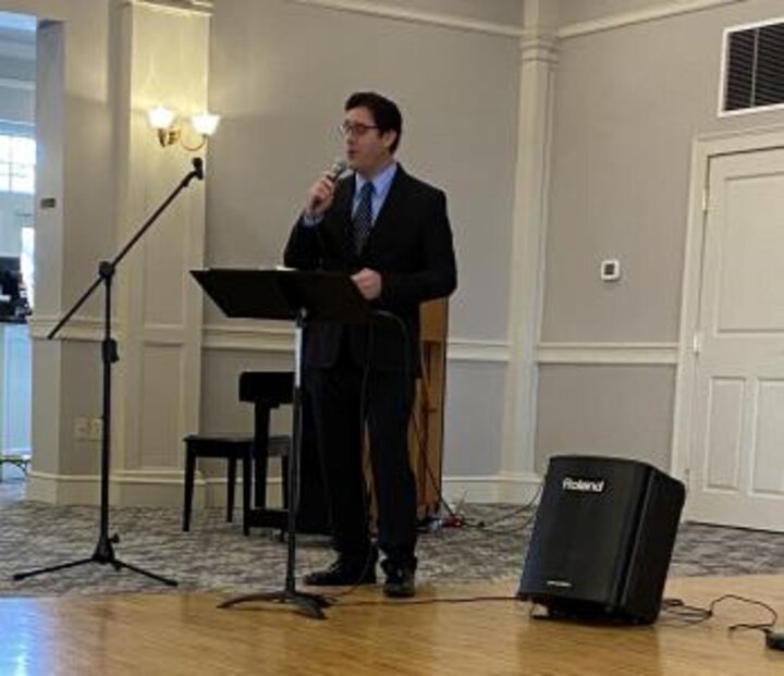 Singer Micheal Tully in black suit with mic and music stand.