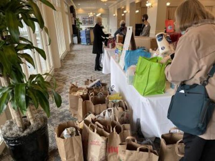 Table and floor covered in bags and sacks filled with food donations.