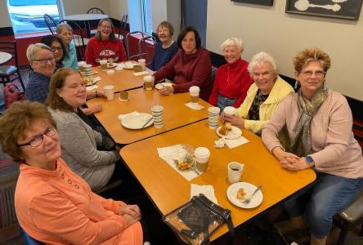 Members sitting at long table at Braeda smile at camera.