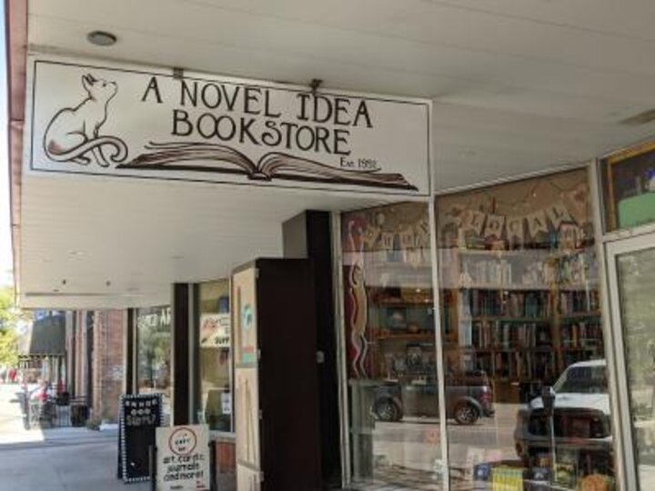 A Novel Idea Bookstore sign of a cat sitting next to an open book.