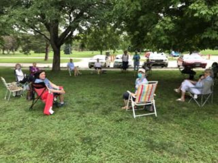 Members sitting in large circle outside in a park.