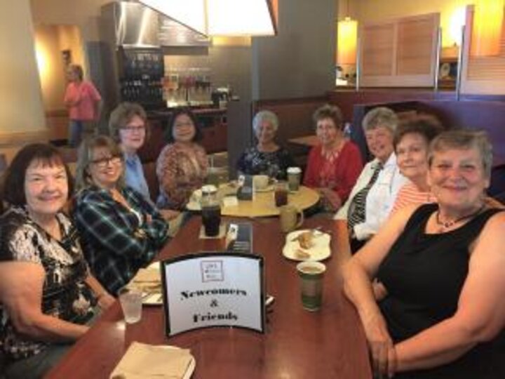 Club members sit at large table at restaurant. 