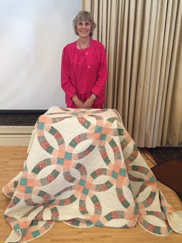 Beth Goble posing behind the quilt she won.
