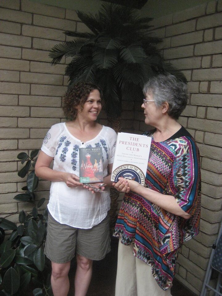 Two women holding book talk with each other.
