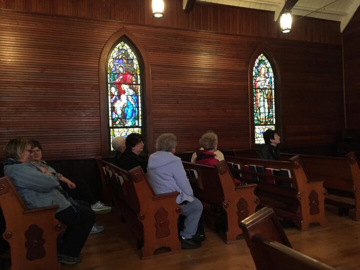 Women's sit in pews inside meager church.
