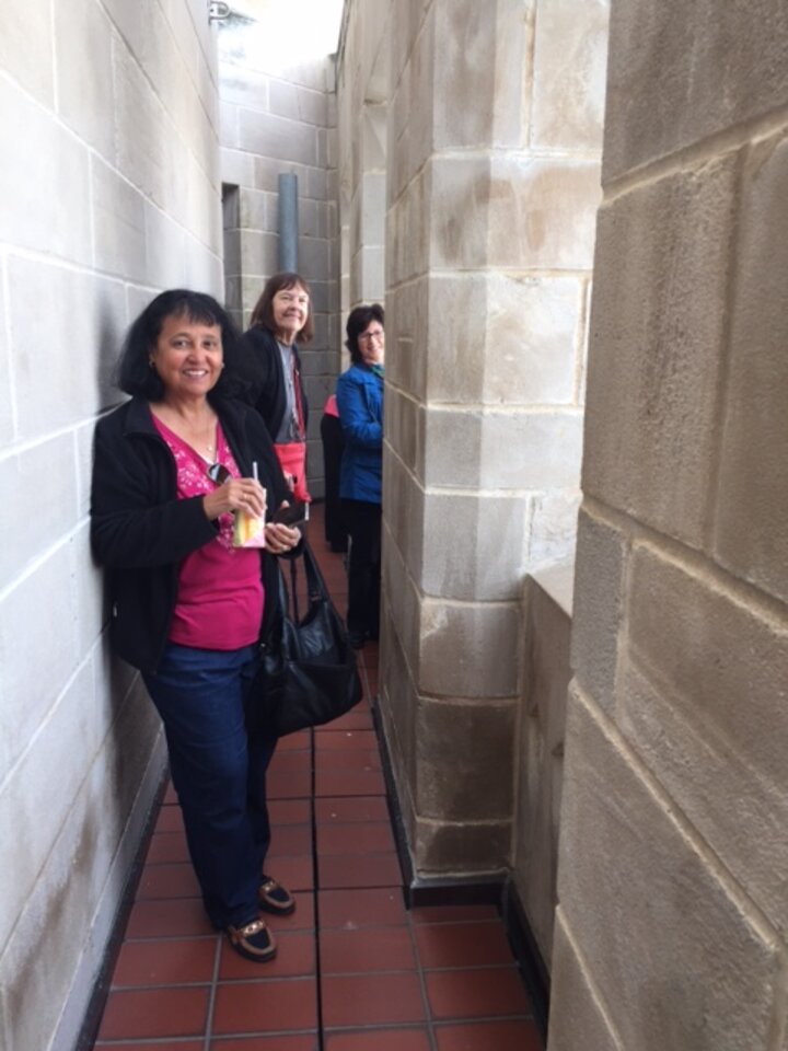 Three women in narrow stone hallway smile at camera.