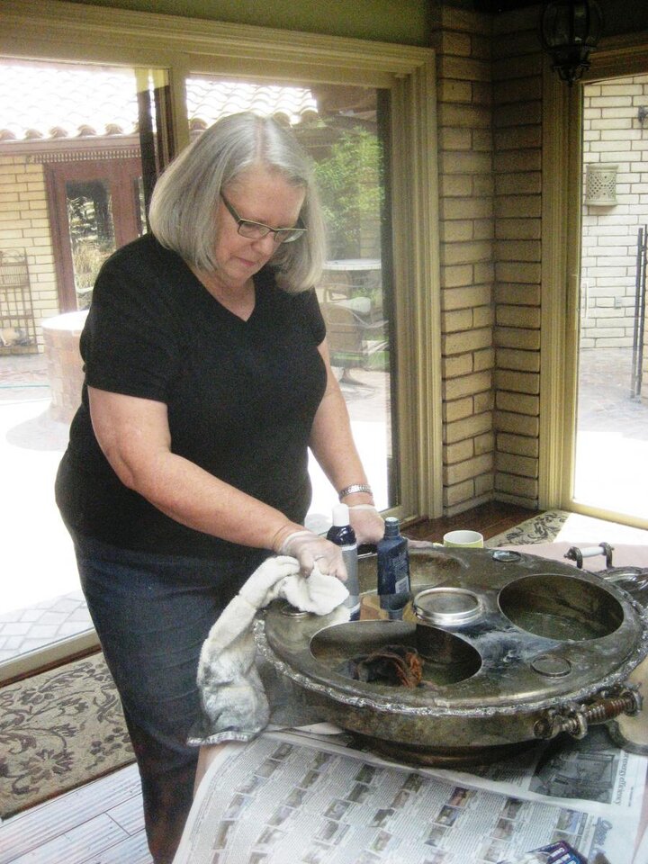 Club member stands at table cleaning large silver basin