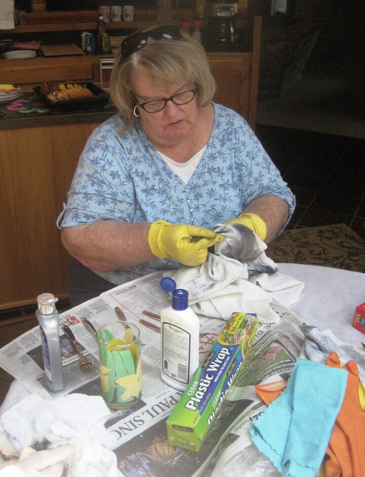 Club member wearing yellow gloves cleans silver cutlery