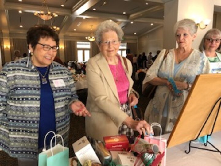 Three women stand by table of gift bags