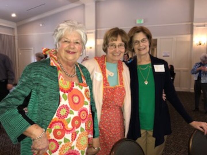 Three women showing off their aprons