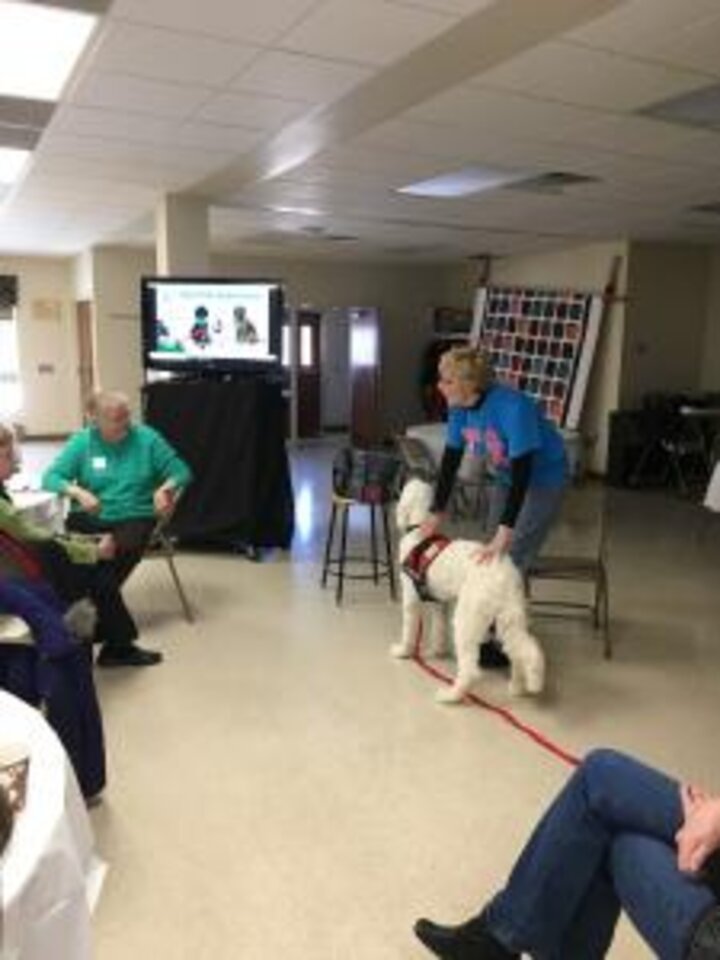 Club members listen to women with dog from Domesti-PUPS.