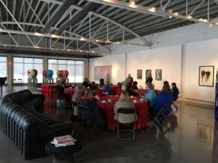 Club members sit around tables at Jun Kaneko ceramic exhibition.